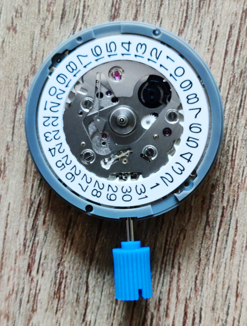 Mouvement NH35 non monté, vu du dessus. Le disque de date est visible, ainsi que la mécanique permettant de faire changer la date.